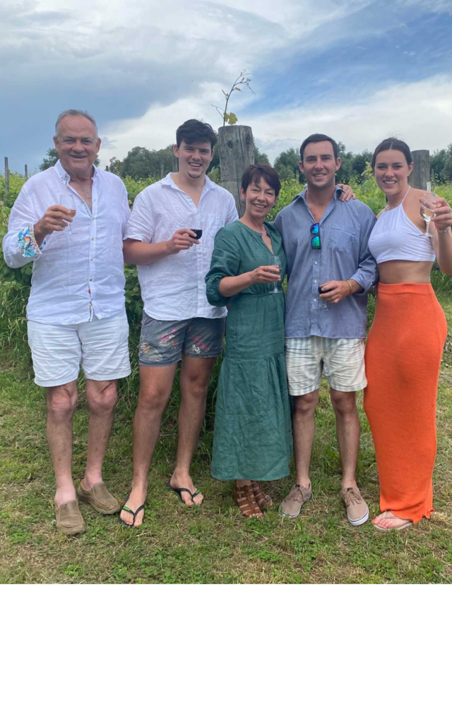 Gerard, Jacqueline, Daniel, Ainsley & James Woods in their Vale Creek vineyard with a glass of wine in their hand.