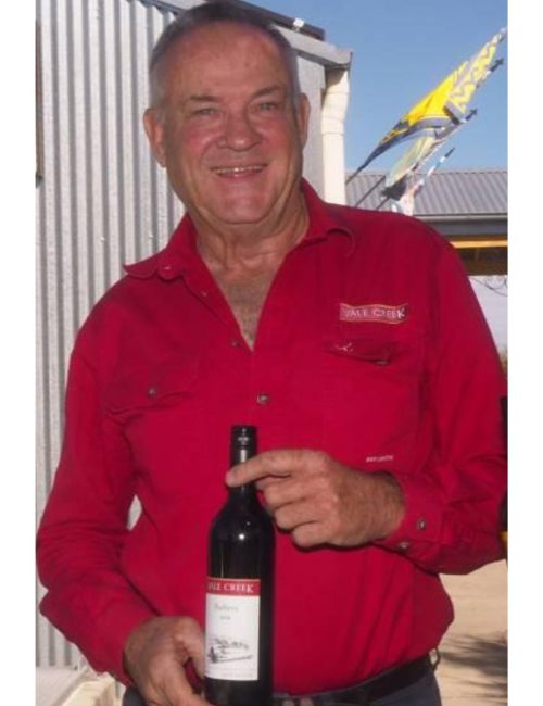 Gerard Woods smmiling at camera holding a bottle of red wines from Vale Creek Wines